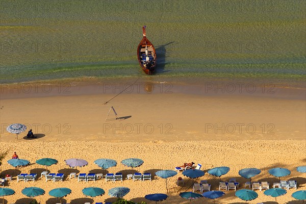 THAILAND, Phuket, Karen Beach, Sun umbrellars on golden sandy beach with boat at shoreline.