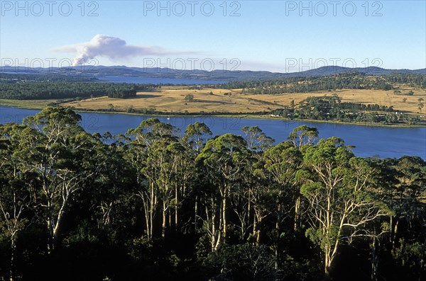 AUSTRALIA, Tasmania, Tamar Valley, Looking north from Brady's Lookout State Reserve towards the Tamar River and a bush fire on horizon in the state's premier wine region.
