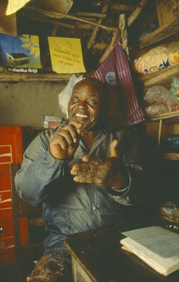MALAWI, Mulanje, Chikondano Village. Disabled male shopkeeper sat in his small shop. Able to run shop due to a community loan.