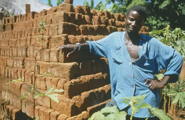 MALAWI, Mulanje, Portrait of man standing next  to brick building in a Ekhamuru Village.