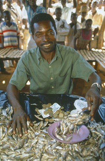 MALAWI, Mulanje, Portrait of male market stall holder selling dried fish. Able to do this due to micro credit loans.