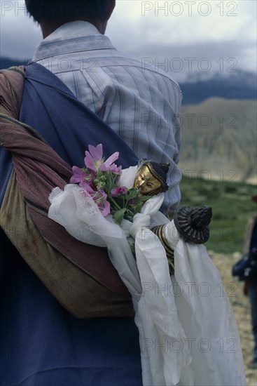 NEPAL, Mustang, Buddha figure wrapped in ceremonial scarves being carried through the summer fields during Lok Khor festival to bring good harvests and protection.