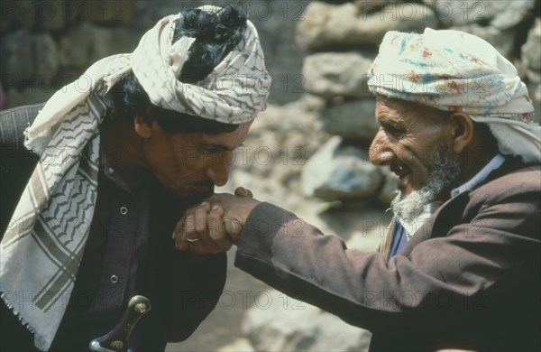 YEMEN, Jebel Aniz, Man kissing the hand of another in traditional Yemen greeting.