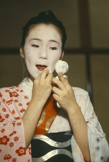 JAPAN, Honshu, Kyoto, Geisha girl applying make up.