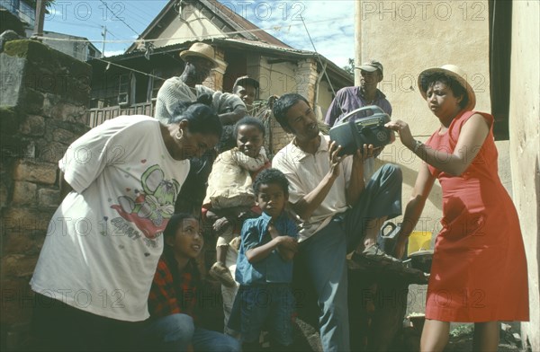 MADAGASCAR, Antananarivo, Group listening to wind up radio.