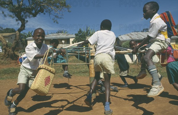 UGANDA, Mengo, Primary school children playing on roundabout. Young boy smoking cigarette.