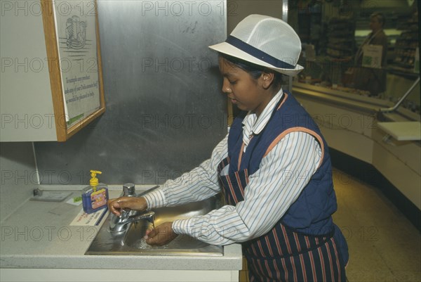 ENVIRONMENT, Hygiene, Washing, Supermarket assistant washing hands at basin of delicatessen counter.