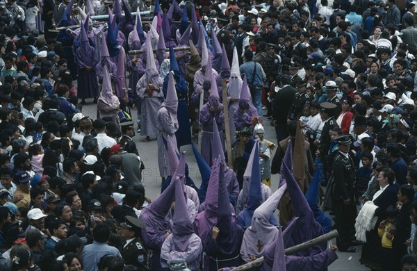 ECUADOR, Pichincha, Quito, Good Friday procession through the Plaza de San Francisco with hooded penitents dragging crosses through the crowds.