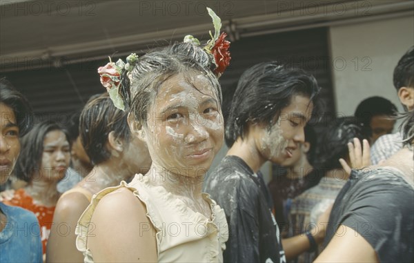 THAILAND, Bangkok, "Crowd covered in mud, young girl with flowers in hair,  celebrating the Songkhran Festival. Thai New Year, 15 April."