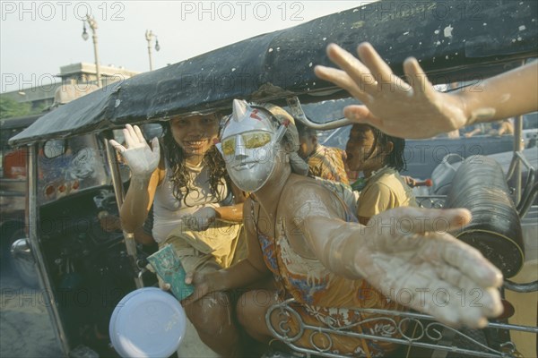 THAILAND, Bangkok, "People in a tuk tuk covered in mud, celebrating the Songkhran Festival. Thai New Year, 15 April."