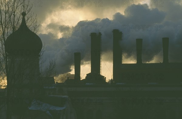 RUSSIA, Moscow, Onion dome roof of the Kremlin with smoke billowing from power station chimneys behind.