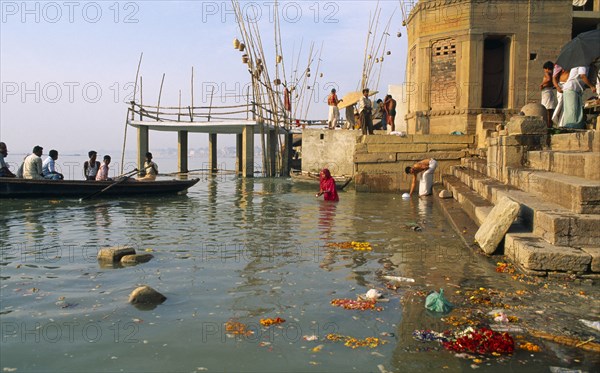 INDIA, Uttar Pradesh, Varanasi, Scum and remnants of flower offerings float around the steps of the ghats on the River Ganges.