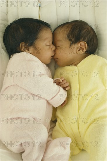 CHILDREN, Twins, "Seven week old fraternal twins in cot, facing each other with hands and faces touching."