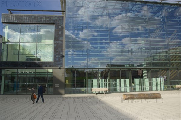 ENGLAND, East Sussex, Brighton, The Library exterior with clouds reflected in the glass and people walking past main entrance.