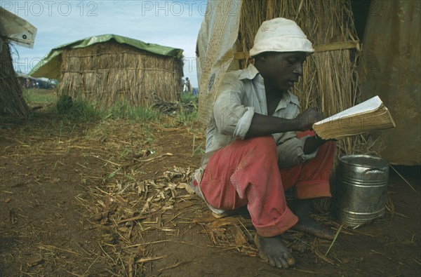 TANZANIA, Heru Oshiuga Camp, Burundian Hutu refugee reading the Bible in refugee camp.
