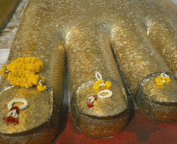 THAILAND, Bangkok, Banglamphu, Wat Indrawiharn. Close up of Floral offerings on the foot of a 45 meter high Gold Buddha.