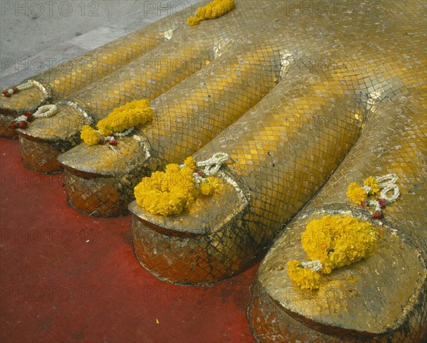 THAILAND, Bangkok, Banglamphu, Wat Indrawiharn. Close up of Floral offerings on the toes of a 45 meter high Gold Buddha.