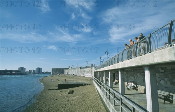 ENGLAND, Hampshire, Portsmouth, Old Portsmouth. Occupied strectch of beach next to the Walls with people looking over railings towards the Square Tower.