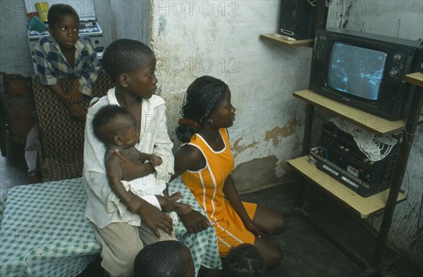 ANGOLA, Luanda, Bairro of Cacuoca.  Fifteen year old Maria Lydia at home watching television with her siblings.  Her family are unable to afford school fees.