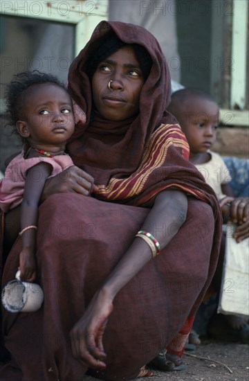 ETHIOPIA, Tribal People, Portrait of young mother with nose ring and facial scarification holding child.