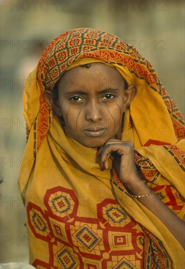SUDAN, Tribal People, Portrait of Eritrean refugee woman with facial scarification and wearing block printed ochre coloured head covering.