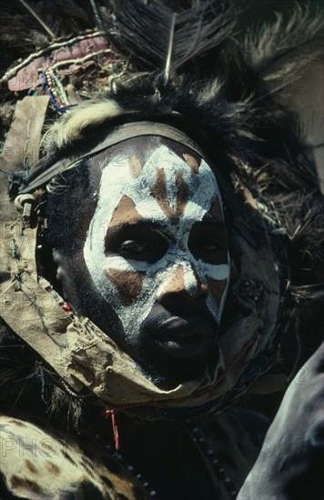KENYA, Tribal People, Portrait of Kikuyu man with painted face and wearing fur and feather head dress.