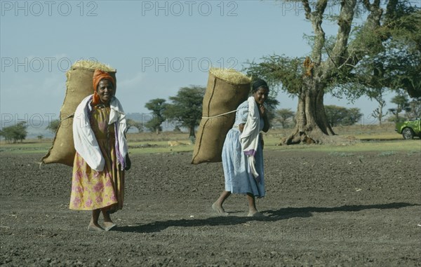 ETHIOPIA, Work, Two women carrying sacks of hay on their backs.