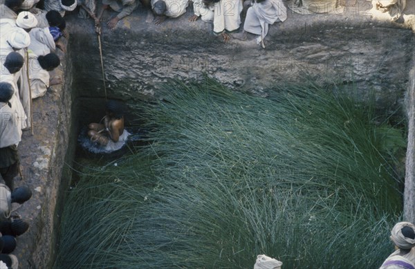 ETHIOPIA, Lalibela, Girl immersed in pool to increase fertility.