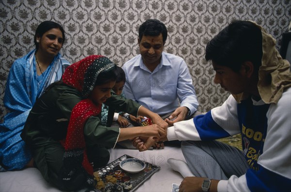ENGLAND, Religion, Hindu, Sacred thread is fastened at the wrist of adolescent boy during Hindu male rite of passage.
