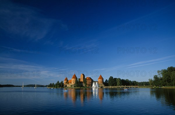 LITHUANIA, Trakai, "Wide angle view of castle reflected in lake with windswept clouds above,"