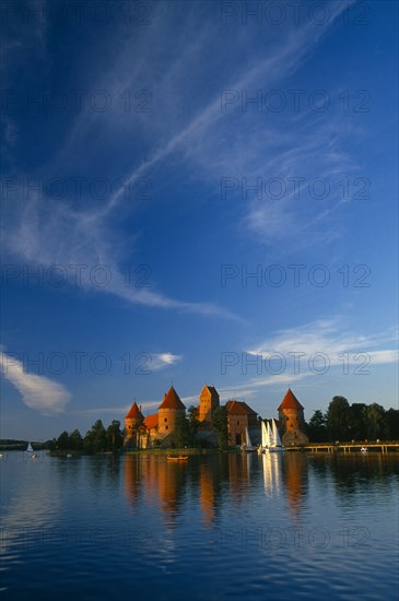 LITHUANIA, Trakai, "Wide angle view of castle reflected in lake with windswept clouds above,"