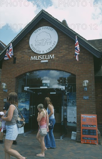 ENGLAND, Hampshire, Lyndhurst, New Forest Museum and library entrance with people walking past.