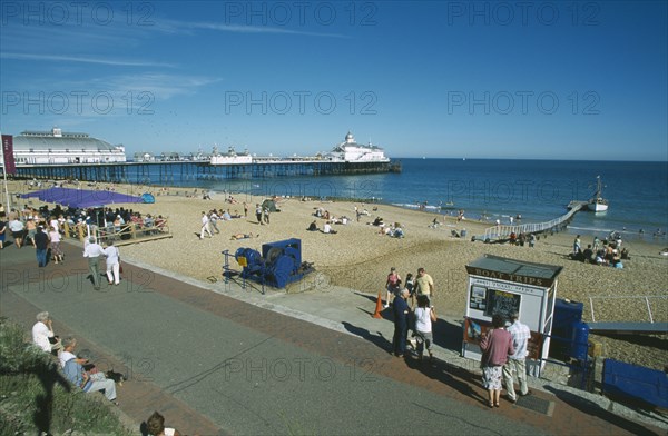 ENGLAND, East Sussex, Eastbourne, View from promenade across busy beachfront and pier.