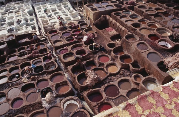 MOROCCO, Fes, Chouwara Tanneries.  Elevated view over men working in the tanner’s pits.