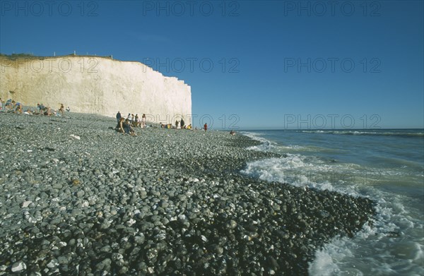 ENGLAND, East Sussex, Birling Gap, Occupied peeble beach with waves lapping and section of cliff face.