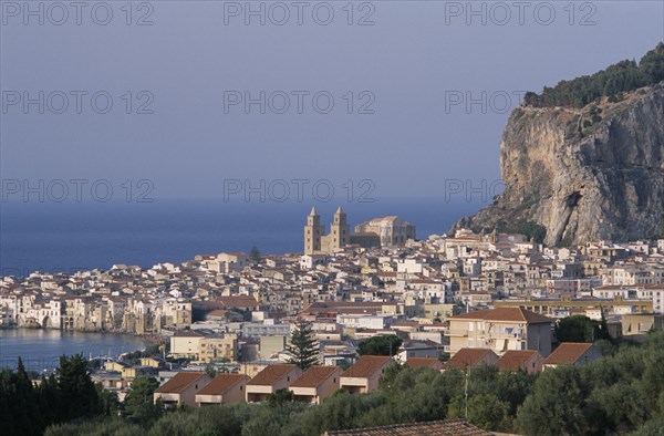 ITALY, Sicily, Palermo, Cefalu. Elevated view over coastal town rooftops and hills towards the sea