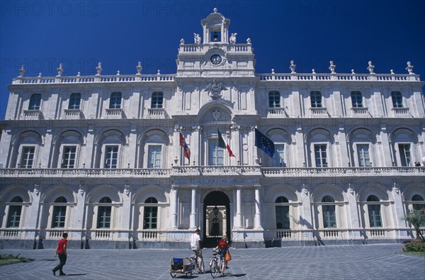 ITALY, Sicily, Catania, Classical architecture of the Gymnasium exterior with people on bicycles in the foreground