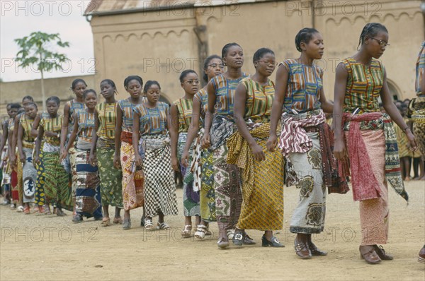 CONGO, Kimpese, Line of female dancers wearing colourful textiles at festival and watching crowd behind.