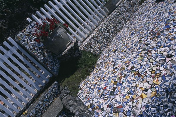 UNITED KINGDOM, Channel Islands, Guernsey, St Andrews. Les Vauxbelets.The Little Chapel. Detail of china fragments with an Urn next to white fence.