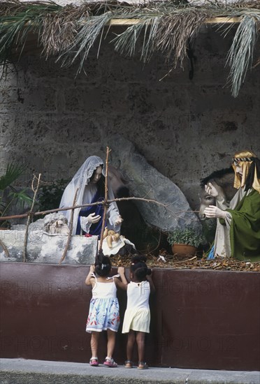 CUBA, Havana, Two young girls admiring a nativity show.
