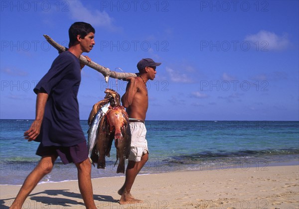 CUBA, Baracoa, Fishermen with freshly caught fish on a beach.