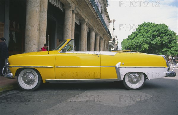 CUBA, Havana, "A classic yellow US 1950s car, parked on the Malecon."