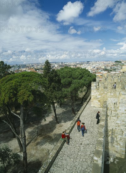 PORTUGAL, Lisbon, Tourist visitors on fortified walls of Castelo de Sao Jorge  with city stretched out beyond.