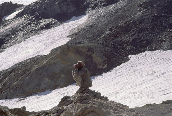 PAKISTAN, North West Frontier Province, Chitral, Hill tribe hunter with Tirich Mir in the background.