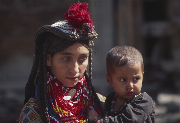 PAKISTAN, North West Frontier Province, Rumbur valley, "Mother wearing lots of colourful beaded necklaces, holding Kalash boy."