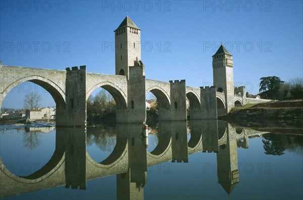 FRANCE, Midi Pyreees Lot , Cahors, Pont Valentre. Bridge with two towers and it’s reflection in the river.