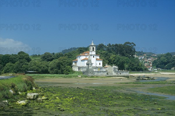 SPAIN, Asturias, Barro, Traditional white church with bell tower and graveyard. Building alone in a field.