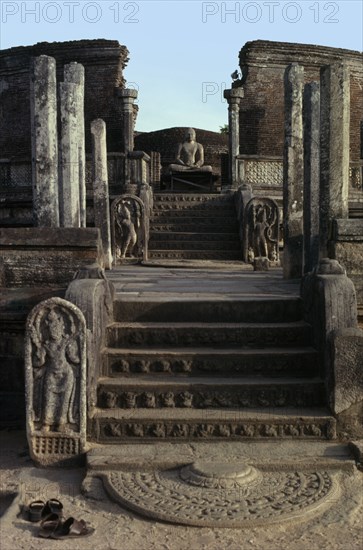 SRI LANKA, Polonnaruwa, Vatadage circular relic house.  Moonstone or carved stone doorstep at the northern entrance with seated Buddha figure beyond.