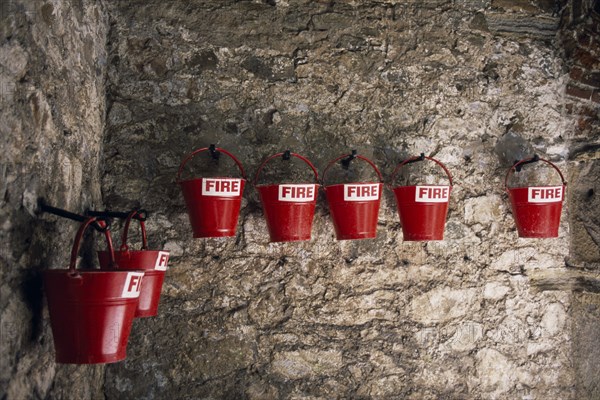 UNITED KINGDOM, Channel Islands, Guernsey, St Peter Port. Castle Cornet. Red fire sand buckets hanging from stone wall