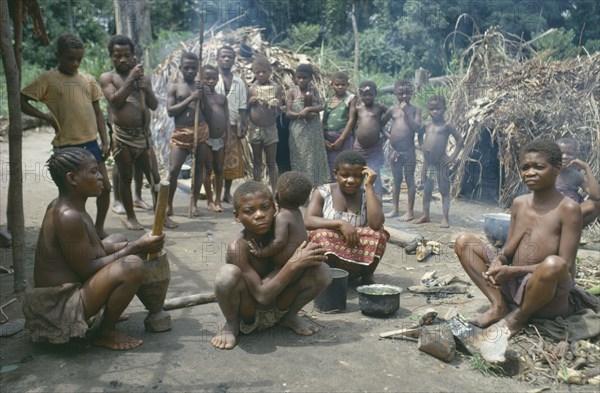 CONGO, Ituri Forest, Pygmy group in village clearing surrounded by thatched huts.